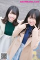 two young women standing next to each other on a street