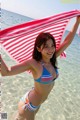 A woman in a bikini holding a red and white striped towel.