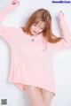 A woman in a pink sweater is posing for a picture.