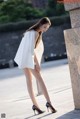 A woman in a white dress and black shoes posing for a picture.