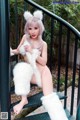 A woman in a white fur outfit sitting on a railing.