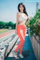 A woman in a white top and orange leggings posing for a picture.