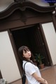 A woman standing in front of a building with a black bag.