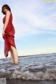 A woman in a red dress standing in the ocean.