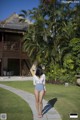 A woman in a blue and white one piece swimsuit walking down a path.